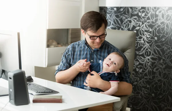 Father with his baby son working at office