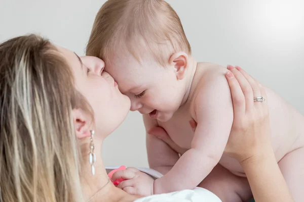 Happy mother kissing 9 months old baby in head