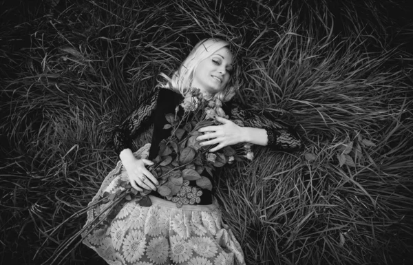 Monochrome portrait of sexy woman with roses lying on field