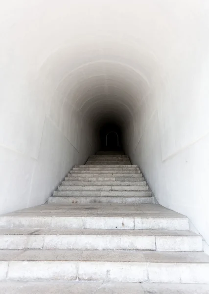 Marble staircase leading to dark tunnel
