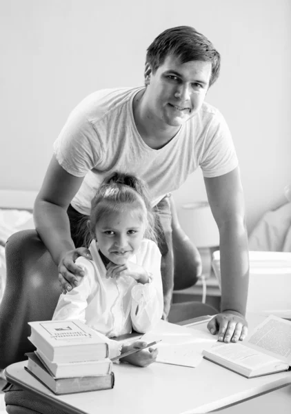 Monochrome portrait of daughter doing homework with father at ho