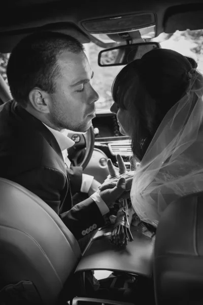 Portrait of bride and groom kissing in car