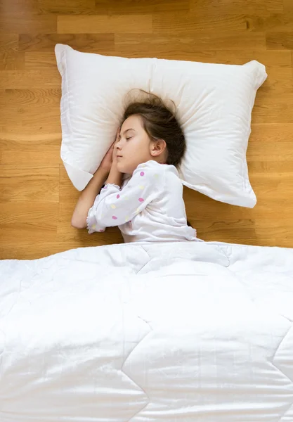 Little girl sleeping on wooden floor on white pillow