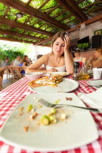 Young woman looking at empty plates at restaurant