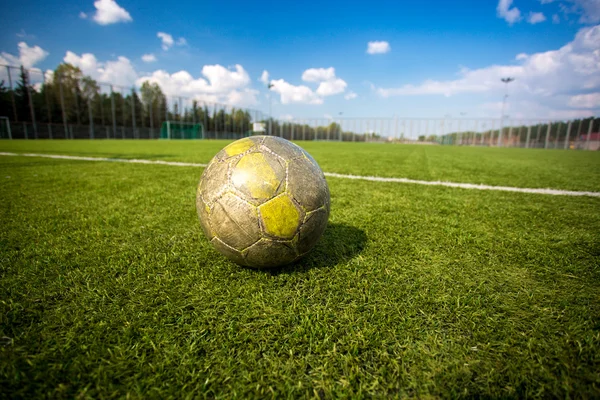 Shabby soccer ball lying on artificial grass field
