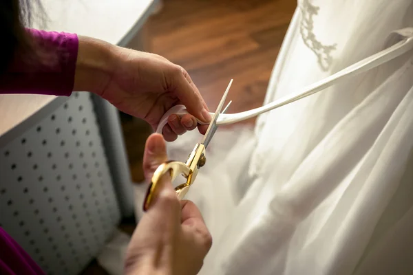 Tailor cutting off ribbon on white wedding dress