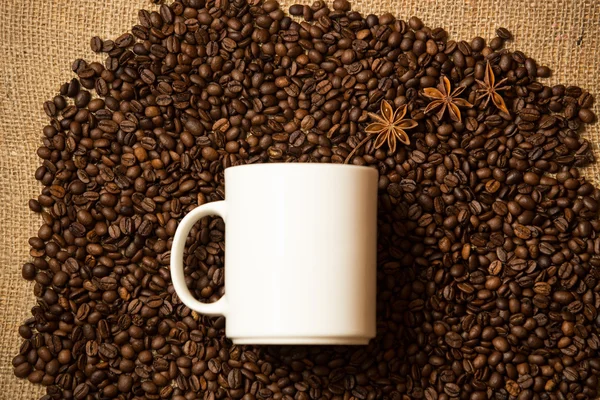 White mug against of coffee background with star anise