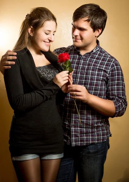Portrait of smiling man giving red rose to cute girlfriend