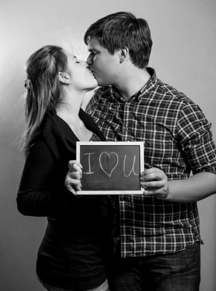 Monochrome portrait of kissing couple in love holding 