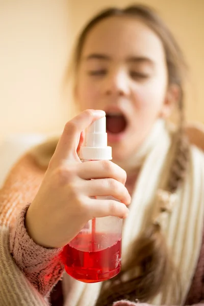 Portrait of sick girl spraying throat