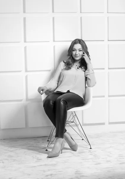 Elegant woman in leggings and shirt sitting on white chair at st