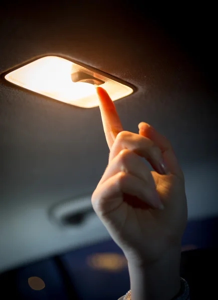 Woman turning light on in car salon