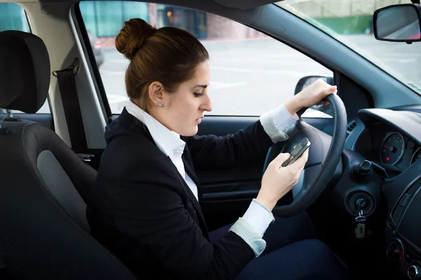Young businesswoman driving a car and using phone