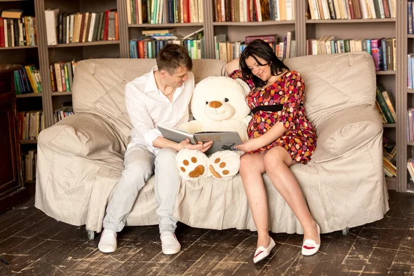 Family waiting for baby reading book to big teddy bear