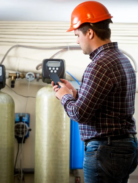 Engineer taking meter readings from industrial pumps at factory