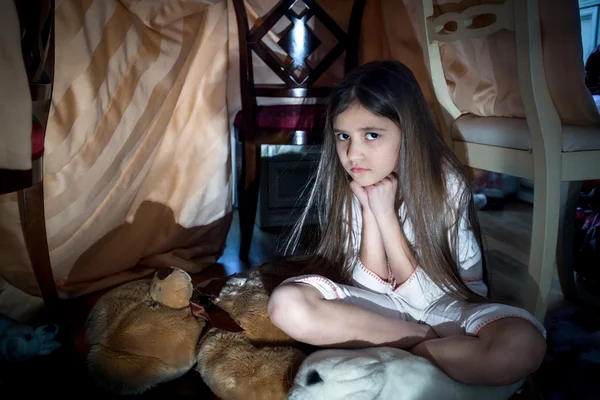 Scared little girl sitting on floor at creepy dark night
