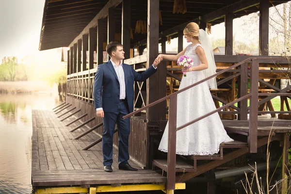 Bride and handsome groom walking down the stairs on pier