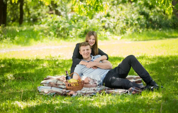 Couple in love lying on blanket under big tree at park