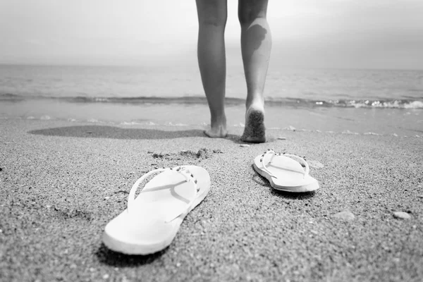 Black and white closeup photo of woman walking into the sea wate