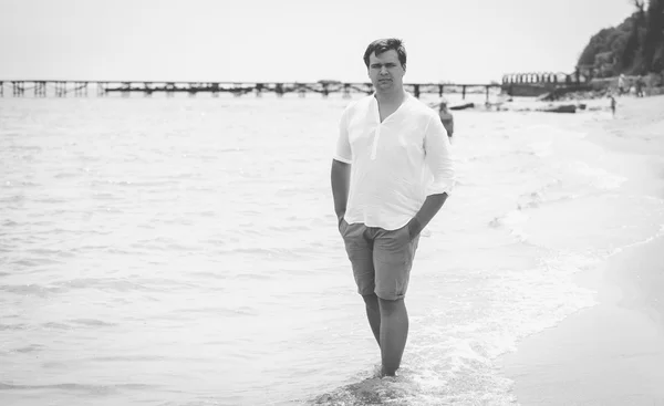 Black and white photo of young stylish man standing on the sea
