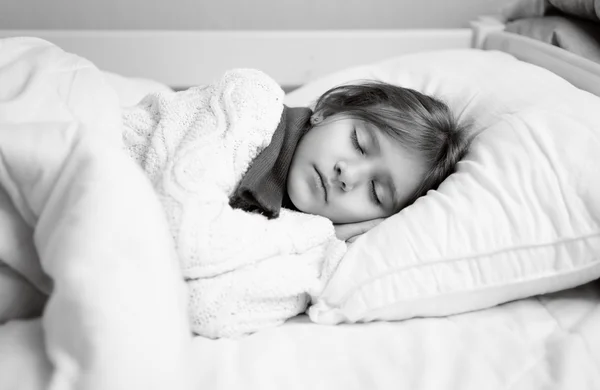 Black and white portrait of girl in sweater sleeping in bed