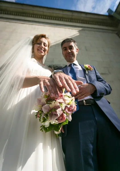 Closeup of bride and groom showing golden rings