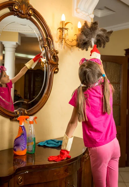 Girl with pigtails cleaning lamp with feather brush