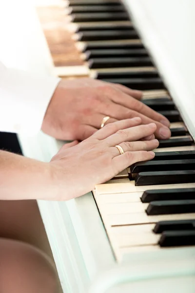 Toned photo of bride and groom wearing rings playing on piano