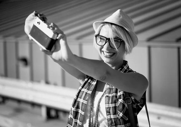 Smiling hipster girl making selfie on vintage film camera