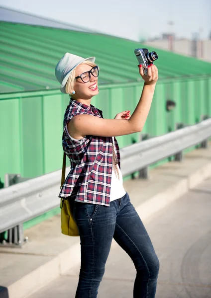 Hipster girl in hat making picture on vintage camera