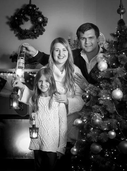 Portrait of happy family posing at Christmas tree with lanterns