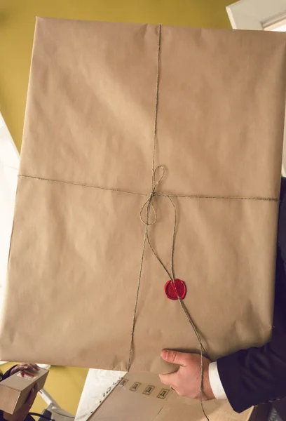 Man carrying parcel packed in paper and sealed with wax