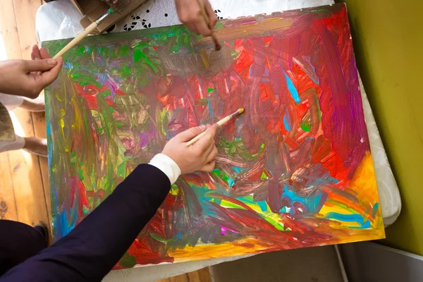 Closeup of people mixing colorful paints on canvas