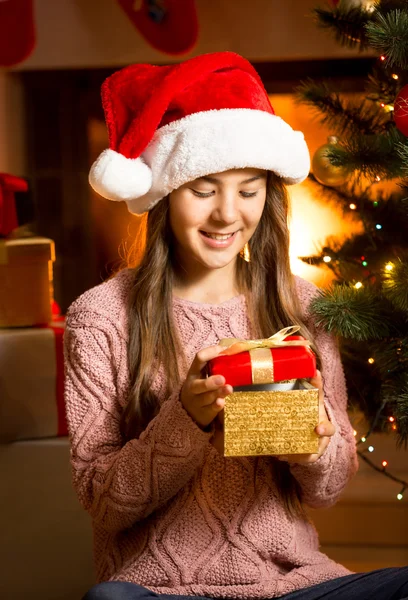 Smiling girl posing with golden Christmas gift box