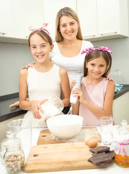 Smiling family making dough for pie on kitchen