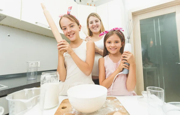 Mother and two daughters posing on kitchen while cooking