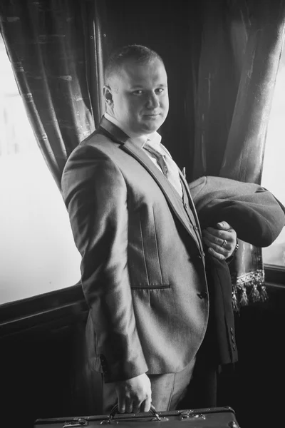 Black and white portrait of man in retro suit posing in train