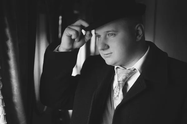 Black and white portrait of man in bowler hat looking out train