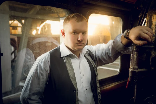 Portrait of handsome man in vintage suit posing in old locomotiv