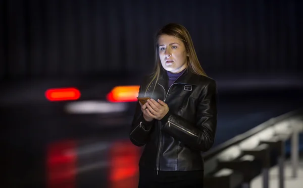 Young woman posing at road at night with mobile phone