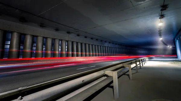 Tunnel under bridge at night with cars rushing