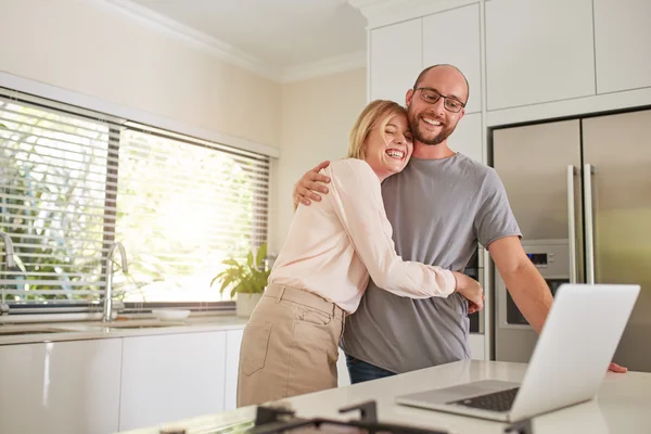 Loving couple in kitchen with a laptop