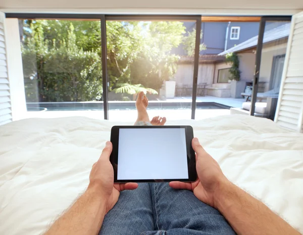 Man using digital tablet while lying on bed