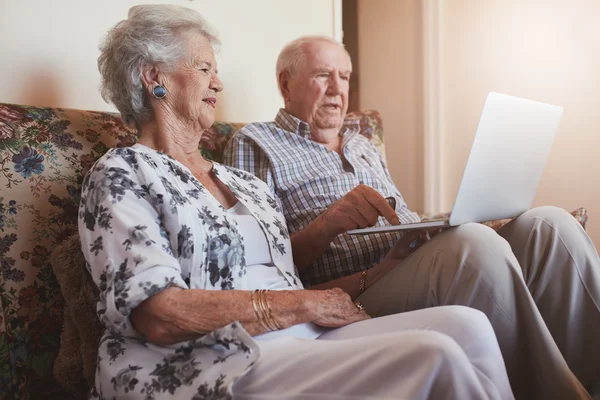 Senior couple sitting on a couch with a laptop