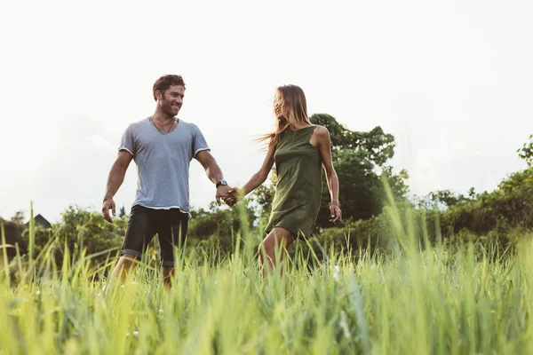 Young couple walking in field of tall grass