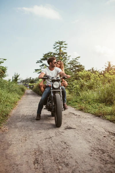 Couple on motorbike driving through dirt road