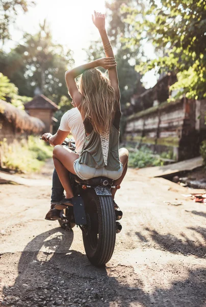 Young couple riding motorcycle on rural road