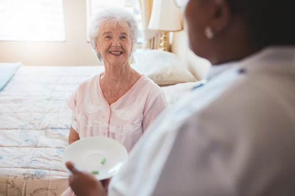 Senior woman on bed with nurse giving medication