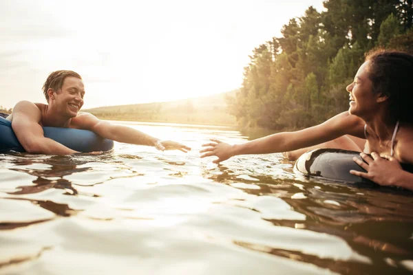 Affectionate young couple floating on inner tubes in lake