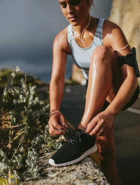 Fitness woman lacing sport shoes before run